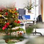 Árbol de Navidad decorado con bolas rojas y doradas junto a un escritorio de oficina, ejemplo de decoración navideña corporativa